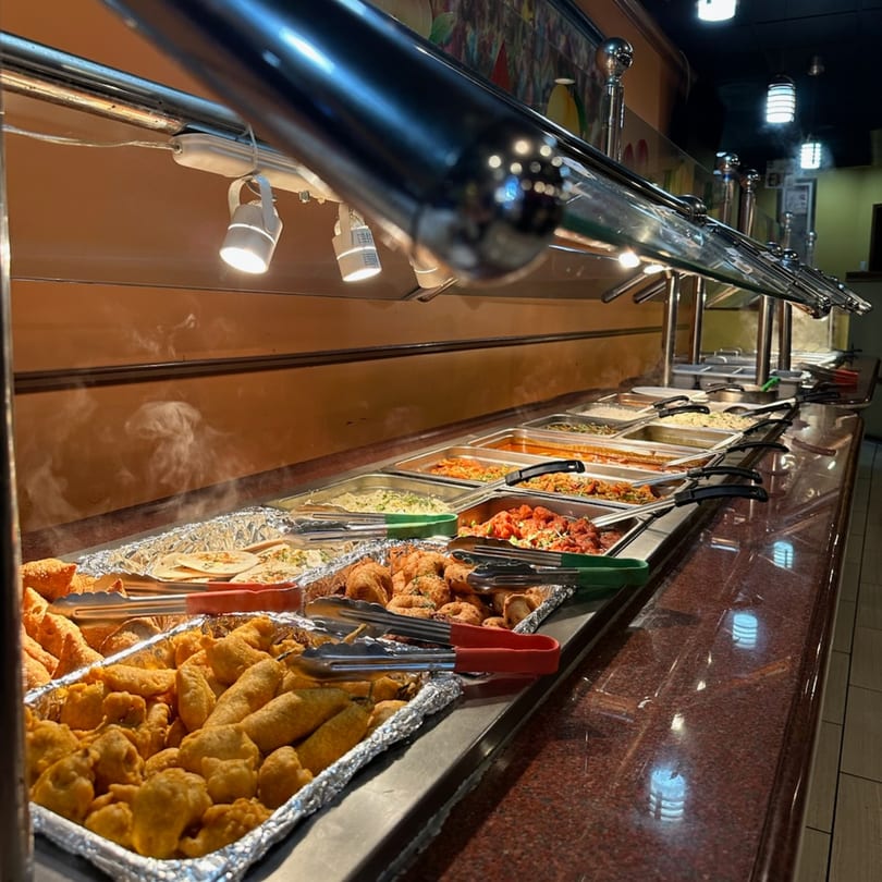 A long buffet line at Mint Leaf Indian Cuisine, filled with various steaming Indian dishes.