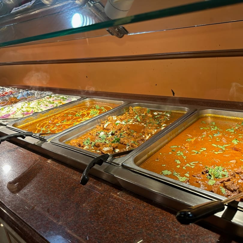 A buffet line at Mint Leaf Indian Cuisine featuring several trays of Indian dishes.