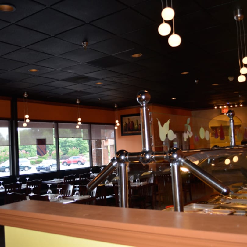 Interior of Mint Leaf Indian Cuisine, showing dining tables, large windows, and a buffet line.