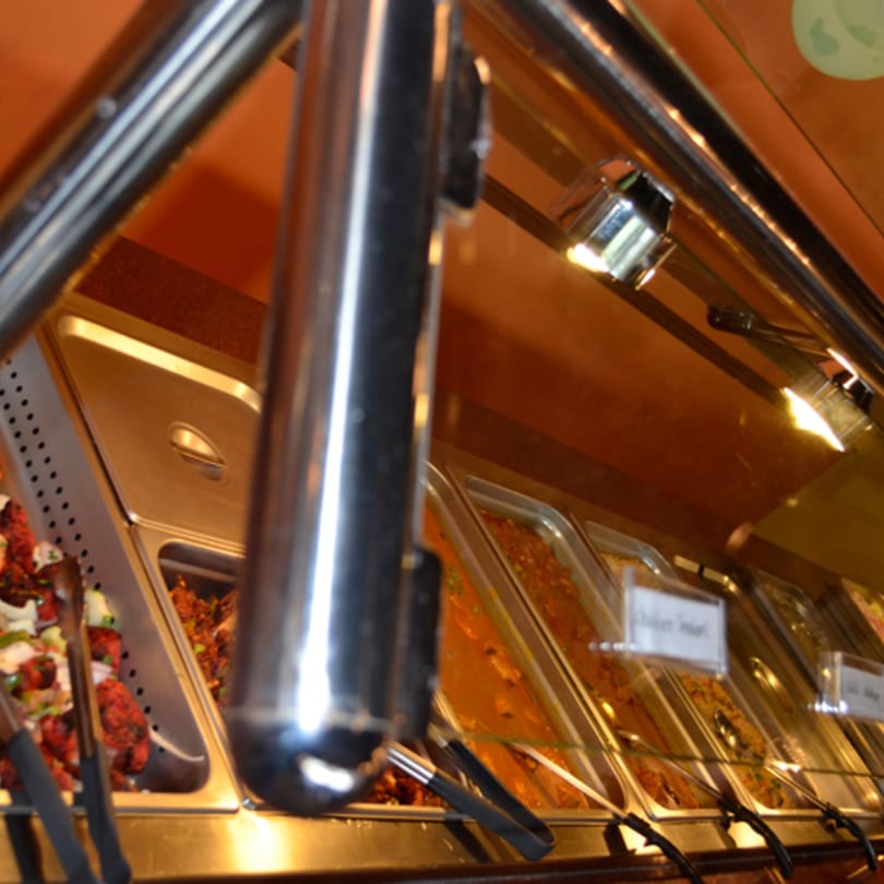 A buffet line at Mint Leaf Indian Cuisine, featuring various Indian dishes in metal serving trays.