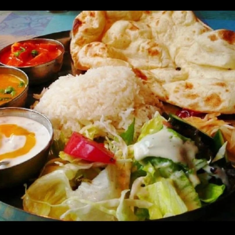 Mint Leaf Indian Cuisine's platter with naan, rice, curries, raita, and a fresh salad.