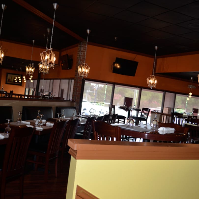 Interior of Mint Leaf Indian Cuisine, showing dining tables set with glasses and chandeliers hanging from the ceiling.