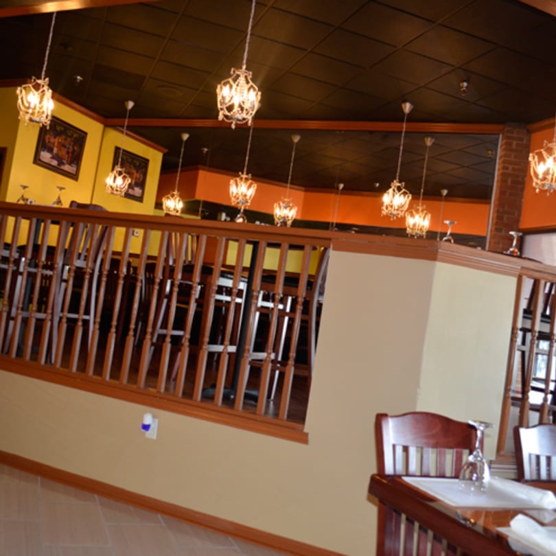 Mint Leaf Indian Cuisine's dining room with ornate chandeliers, wooden railings, and yellow walls.